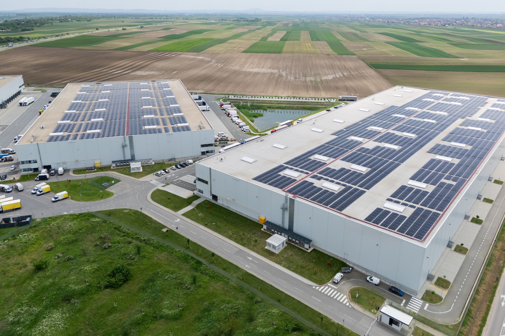 Logistics centers with solar panels on roofs. Aerial view. Drone point of view.